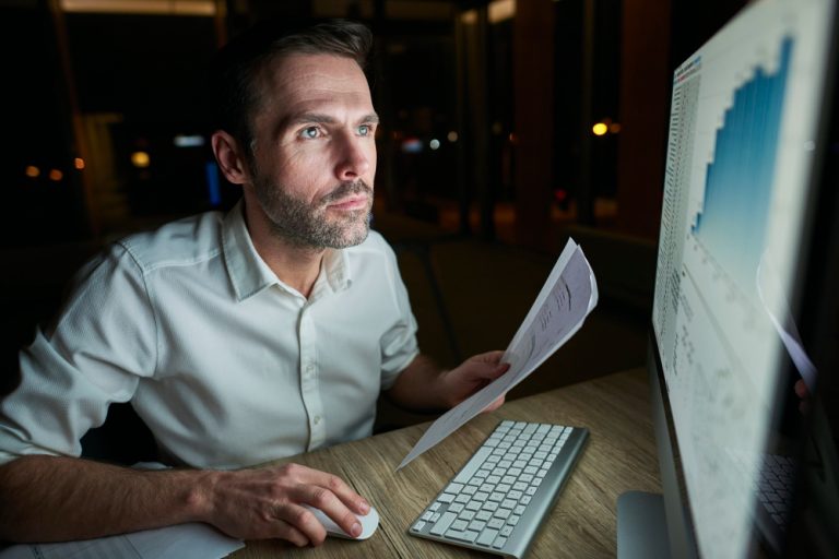 Créditos tributários na Reforma Tributária: executivo analisando relatórios fiscais em computador.
