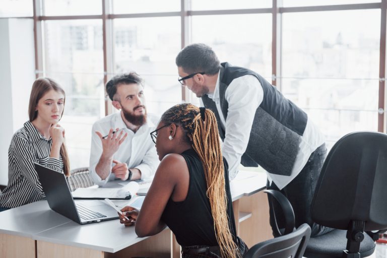 Compliance Operacional: um executivo e três executivas em uma sala de reuniões.