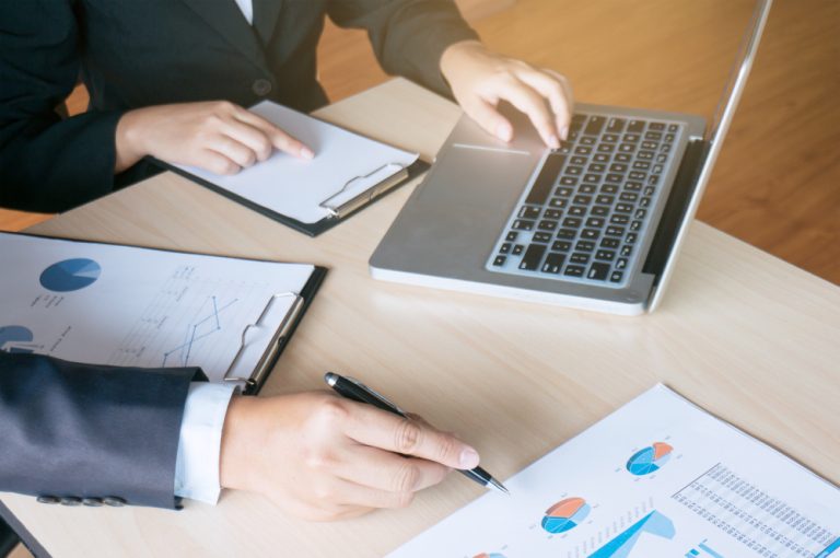 Terceirização contábil BPO: executiva analisando relatórios financeiros e gráficos de balanço em uma mesa de escritório